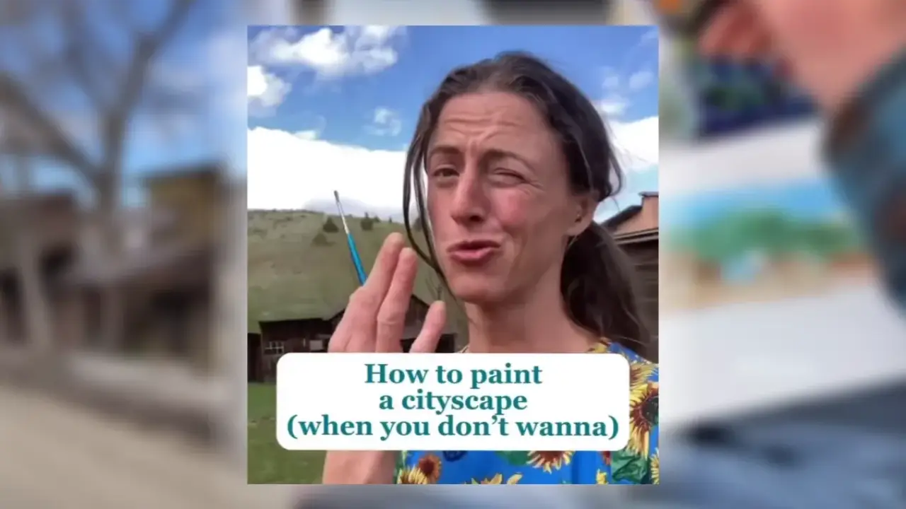 Juliene holding a watercolor brush outdoors with a hillside and buildings behind her, sharing tips for painting a cityscape in watercolor.