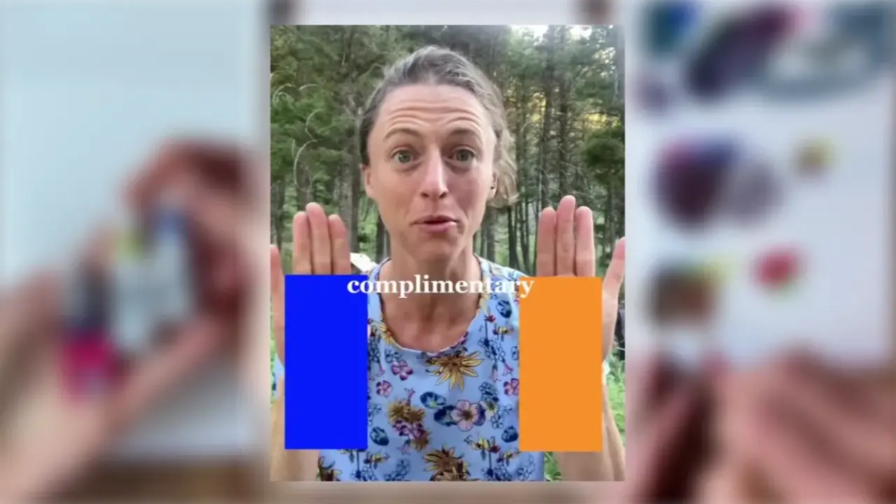 Artist Juliene holds her hands beside blue and orange color blocks outdoors, illustrating complementary colors for mixing black watercolor.