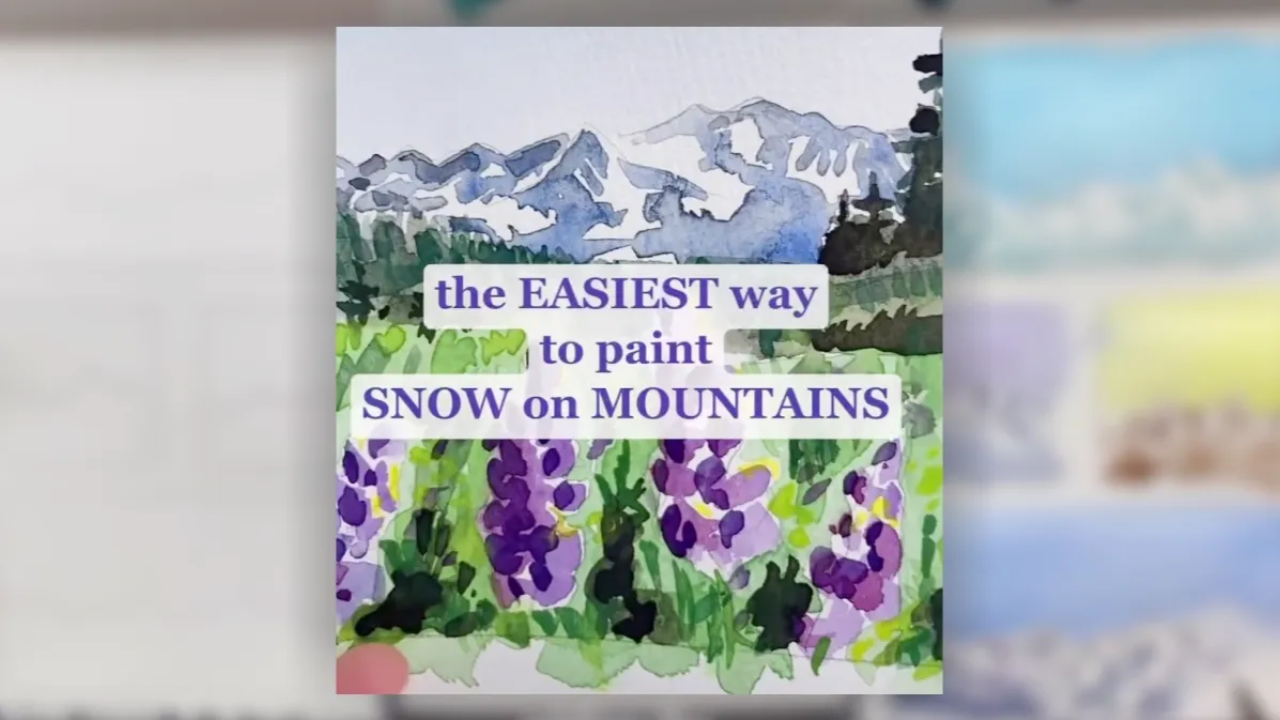 Watercolor painting of snow-covered mountains above green fields and purple wildflowers, demonstrating an easy technique for painting a watercolor snow mountain.