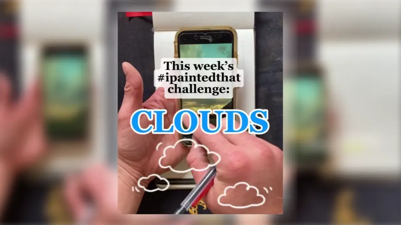 Juliene's hand hold a pen over a phone displaying a landscape reference, with cloud sketches around it for a watercolor cloud sketching tutorial using one-point perspective.