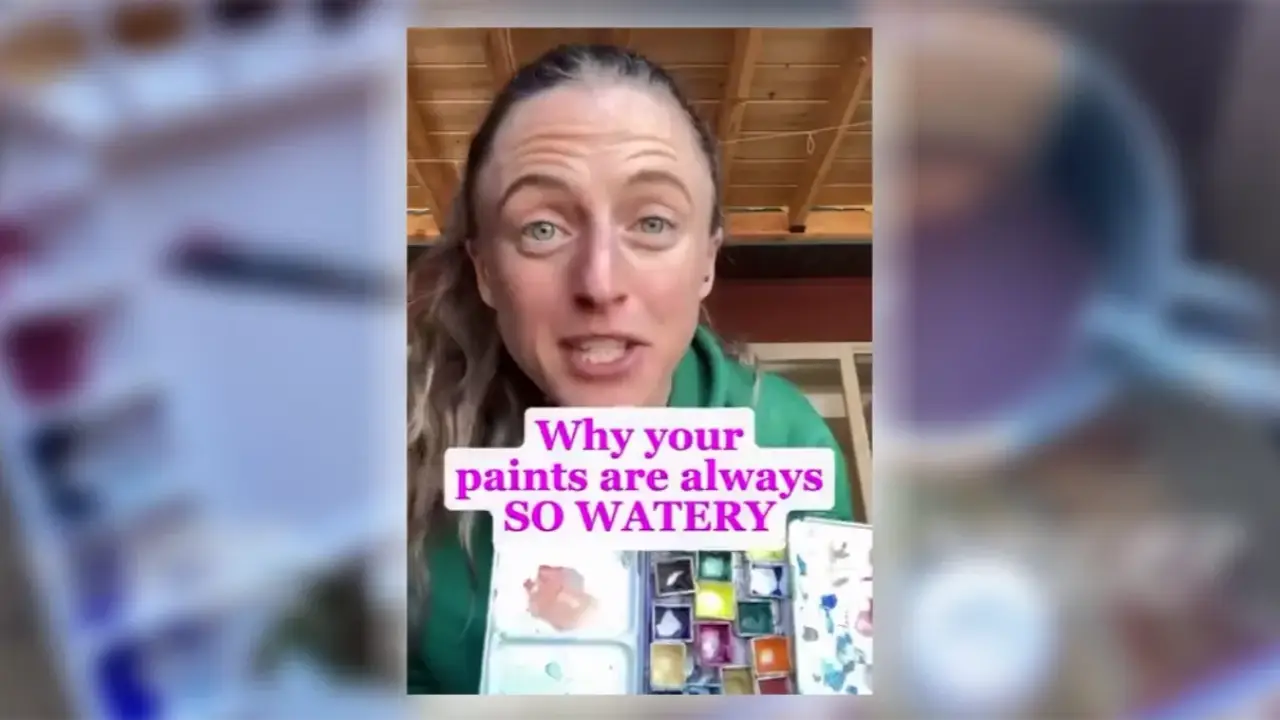 Artist Juliene holding a watercolor palette with watery paint, explaining why watercolor paints become too diluted and how to fix them.