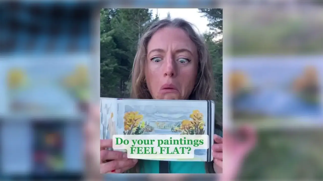 Artist Juliene holds a watercolor landscape showing trees, water, and distant mountains, illustrating atmospheric perspective and why a watercolor painting can look flat.