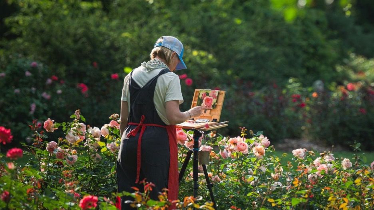 The decision to keep living while you're searching for a job, changes everything.  Woman standing in a garden of roses painting.