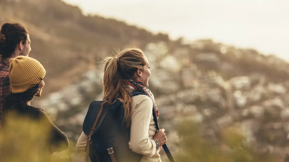 Hikers with backpacks walking together across a sunlit hillside