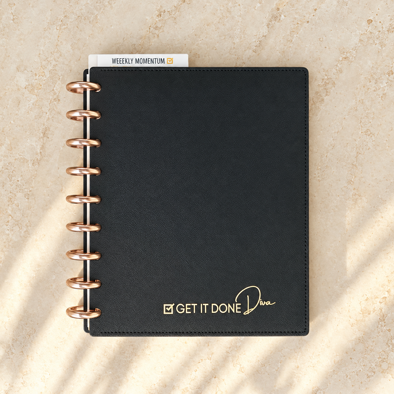 Closed Get It Done 90-Day Planner — black vegan-leather cover with gold-foil logo and rose-gold discs