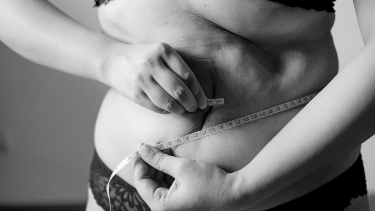 A woman measuring her waist with a tapemeasure