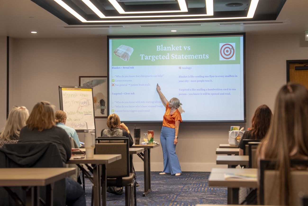 Miranda in an orange top pointing to a slide titled Blanket vs Targeted Statements in front of a room of C.A.s