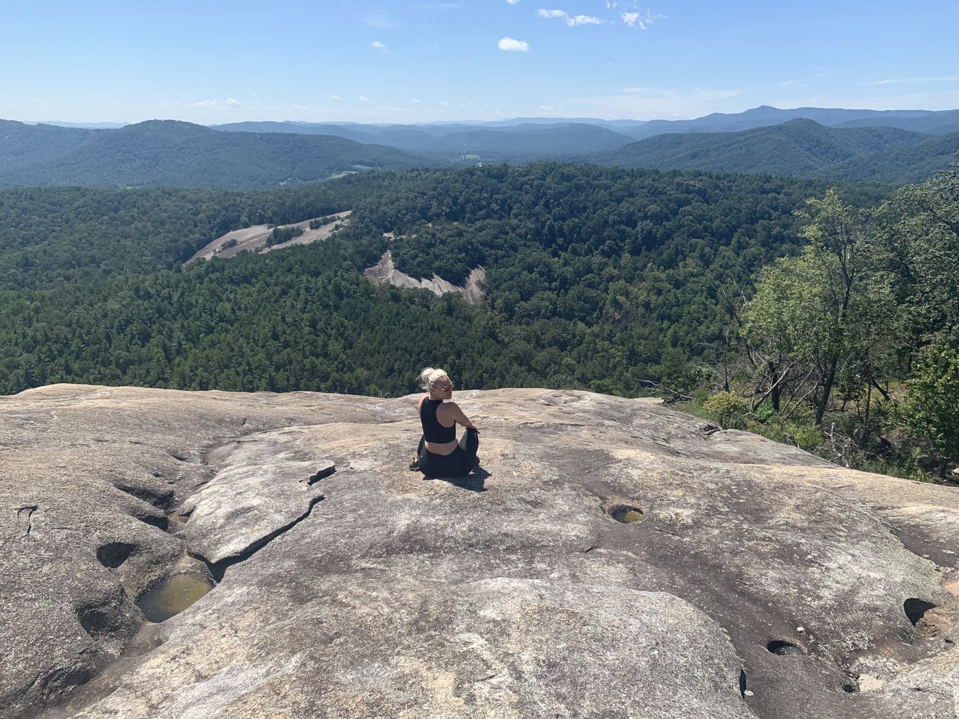 Miranda sitting on a granite overlook above a wide mountain view