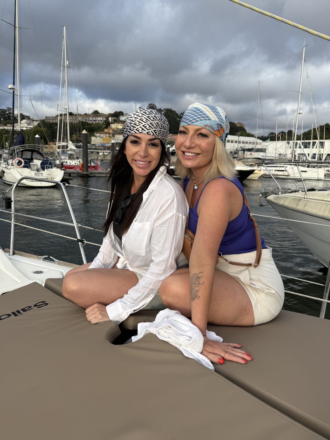 Miranda and Erica on a sailboat in a marina, both wearing headscarves