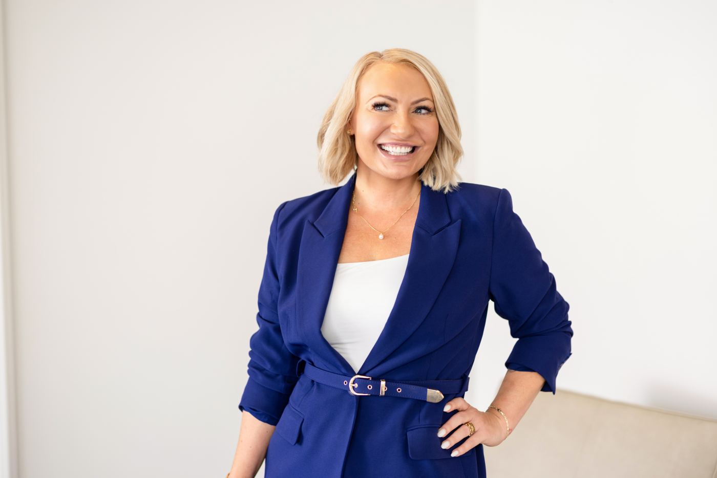 Miranda in a royal blue suit, smiling with her hands on her hips