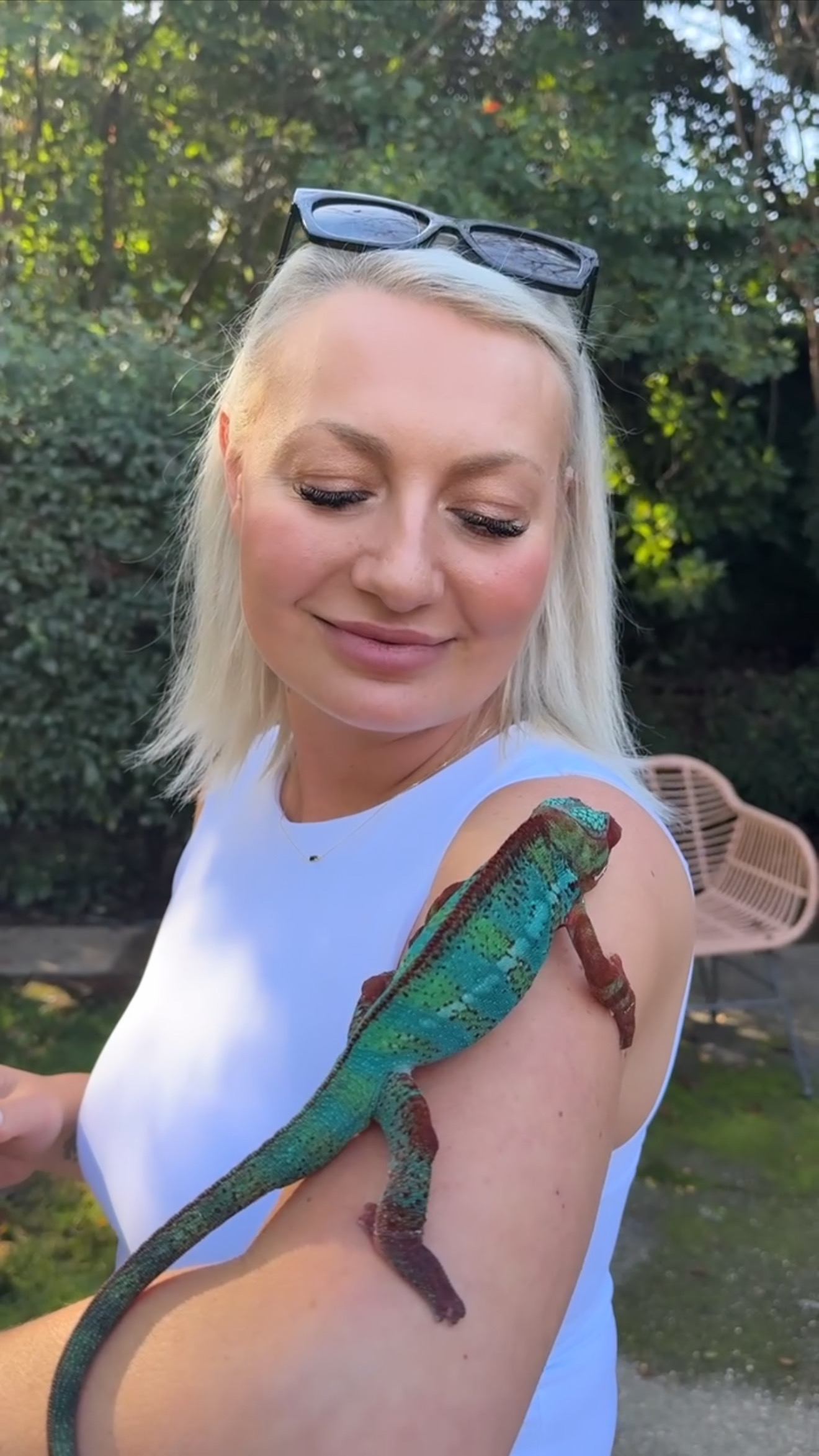 Miranda smiling as Wonka, her green panther chameleon, climbs down her arm