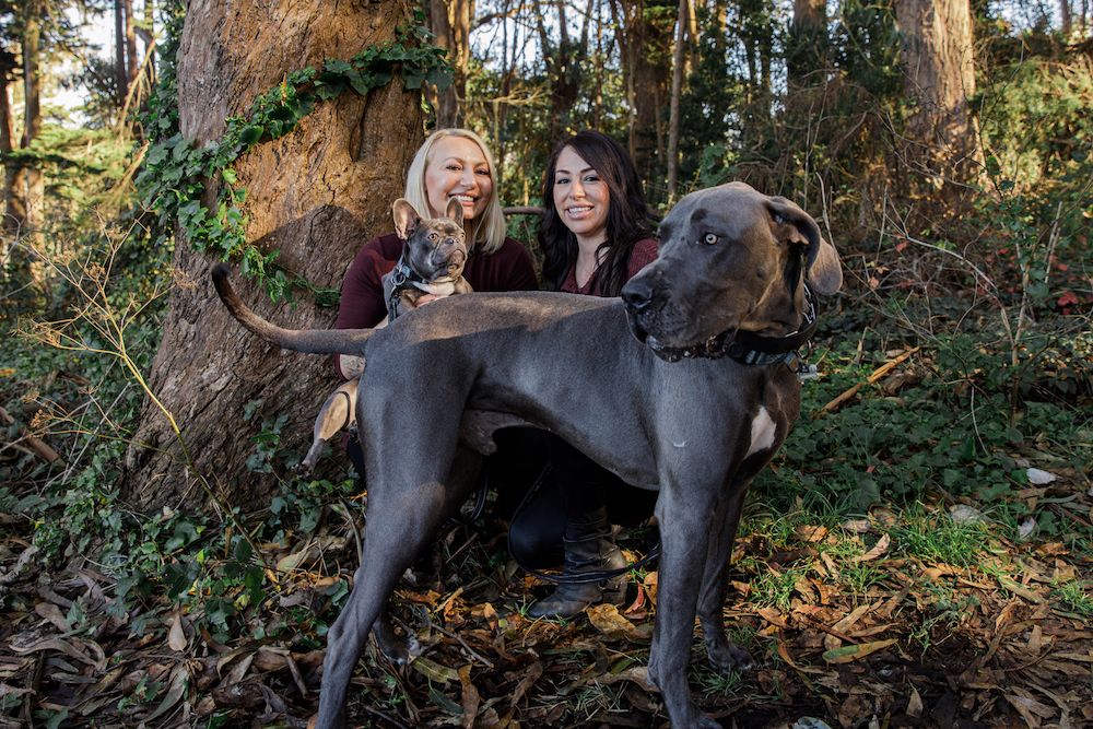 Miranda and Erica in the woods with their Frenchie Harlow and Great Dane Jethro