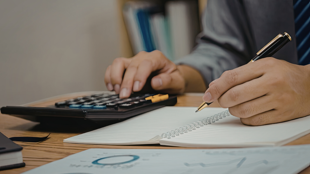 A seller's agent in Rhode Island analyzing multiple real estate offers using a calculator and notebook to determine the best deal.