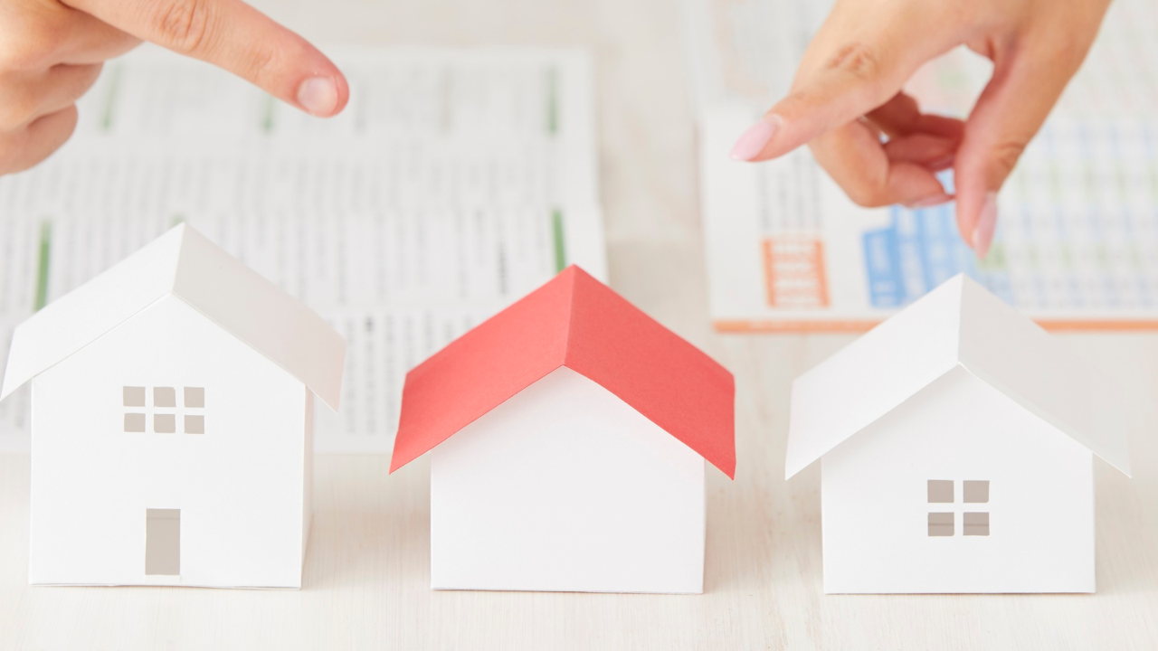 Three paper model houses with hands pointing at them, illustrating why some homes receive multiple offers while others sit on the market.