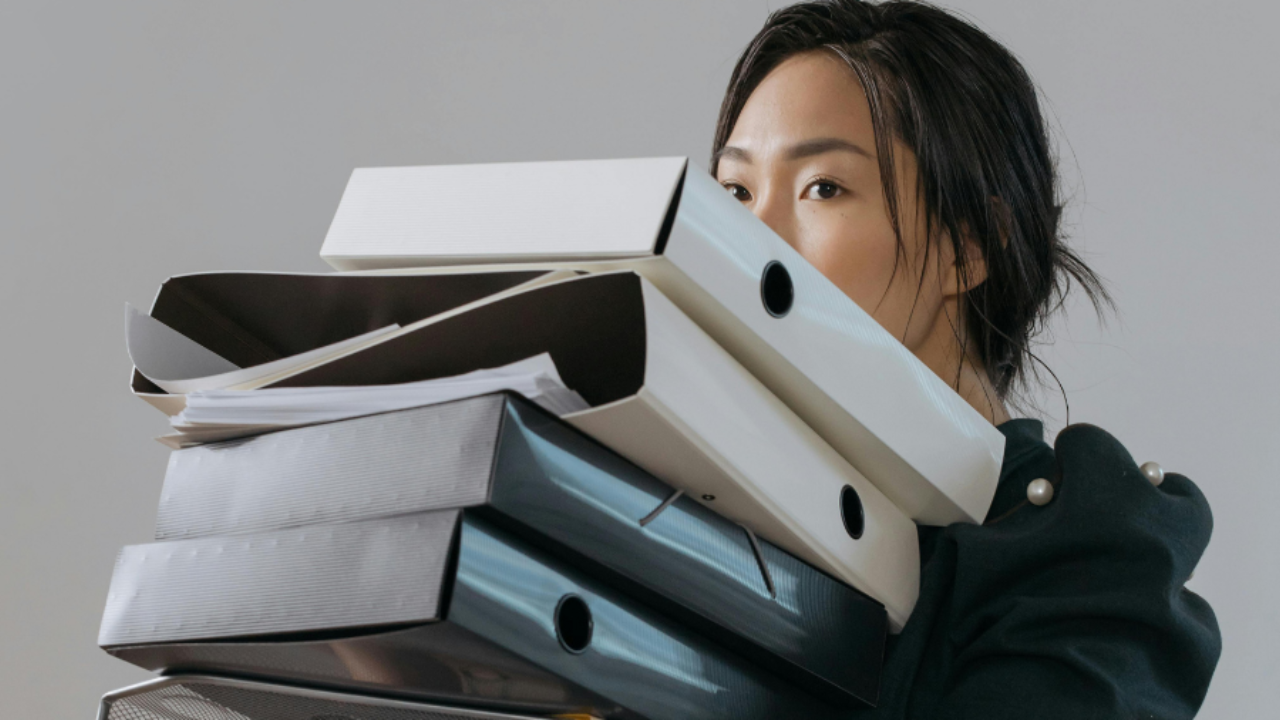 woman carrying a stack of binders up to her eyes