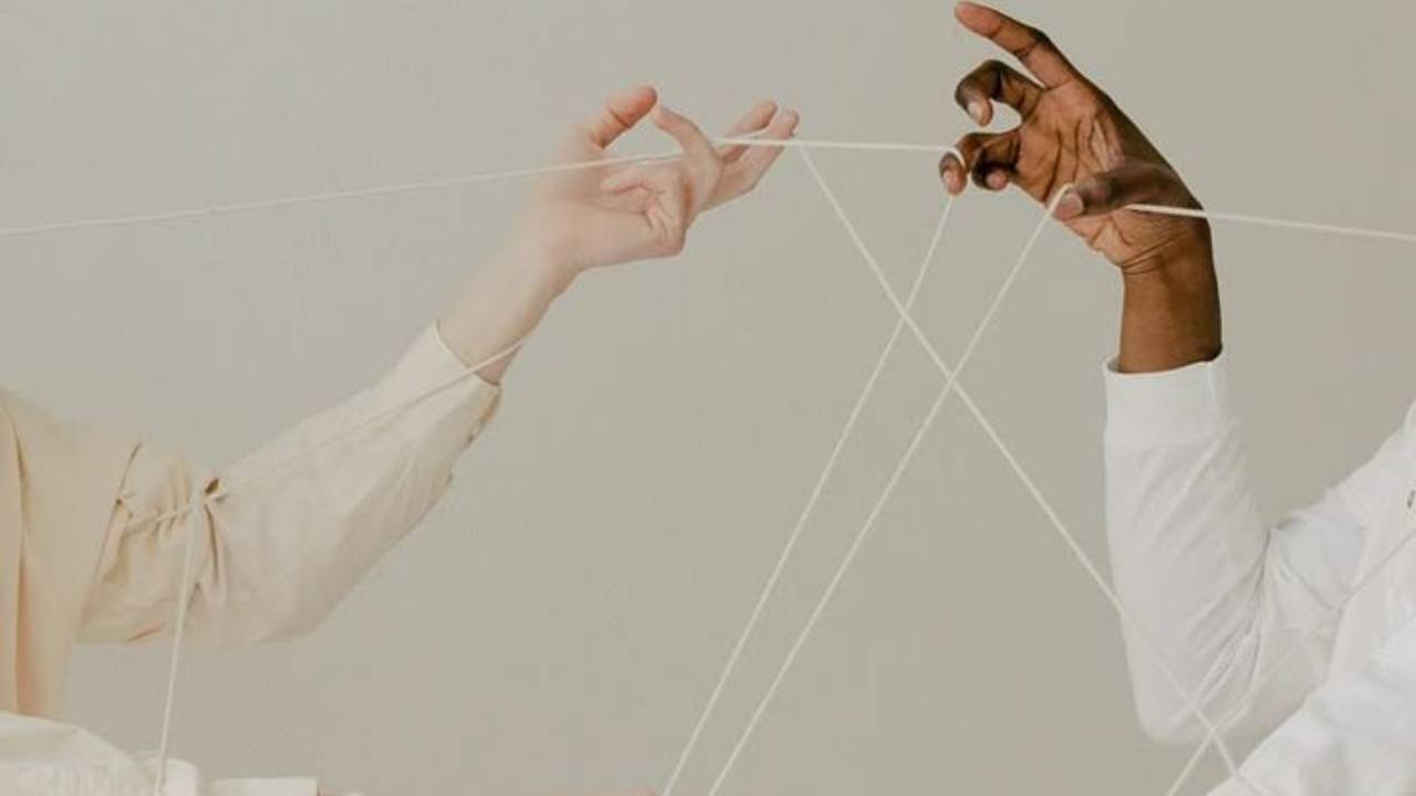 two hands holding crossing strings