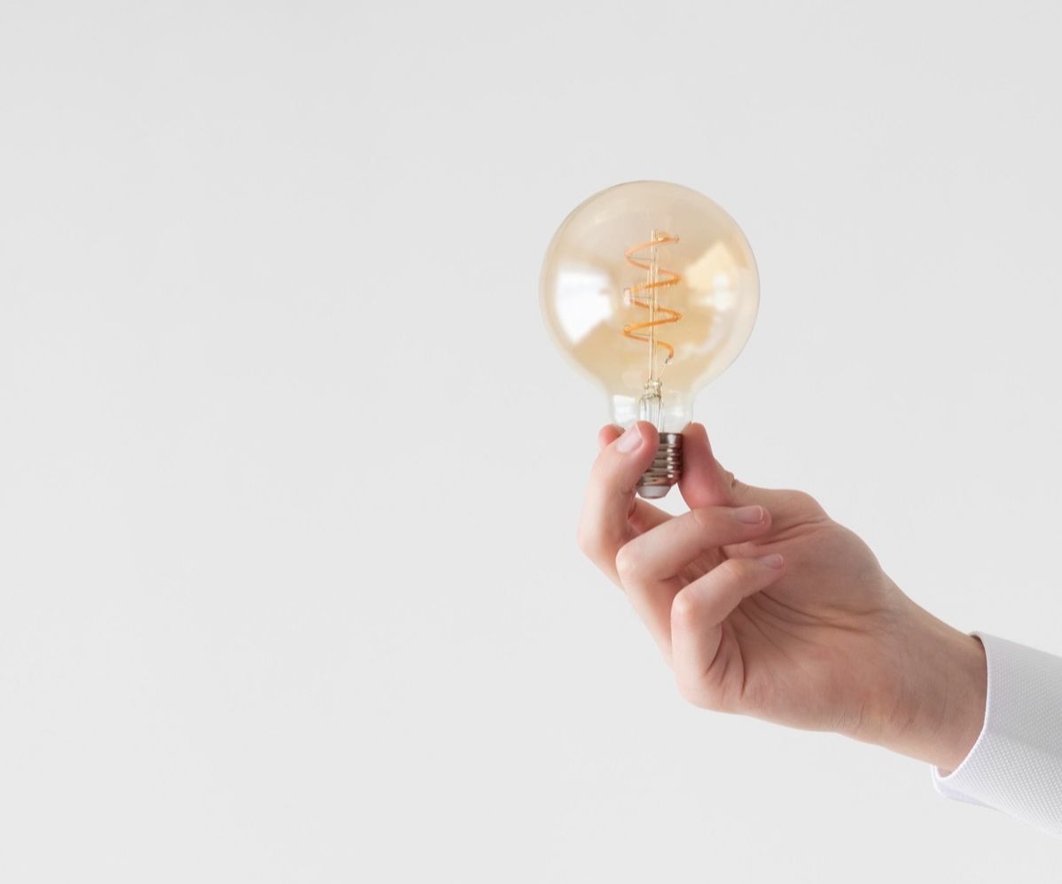 A hand holding a lightbulb with a white background.