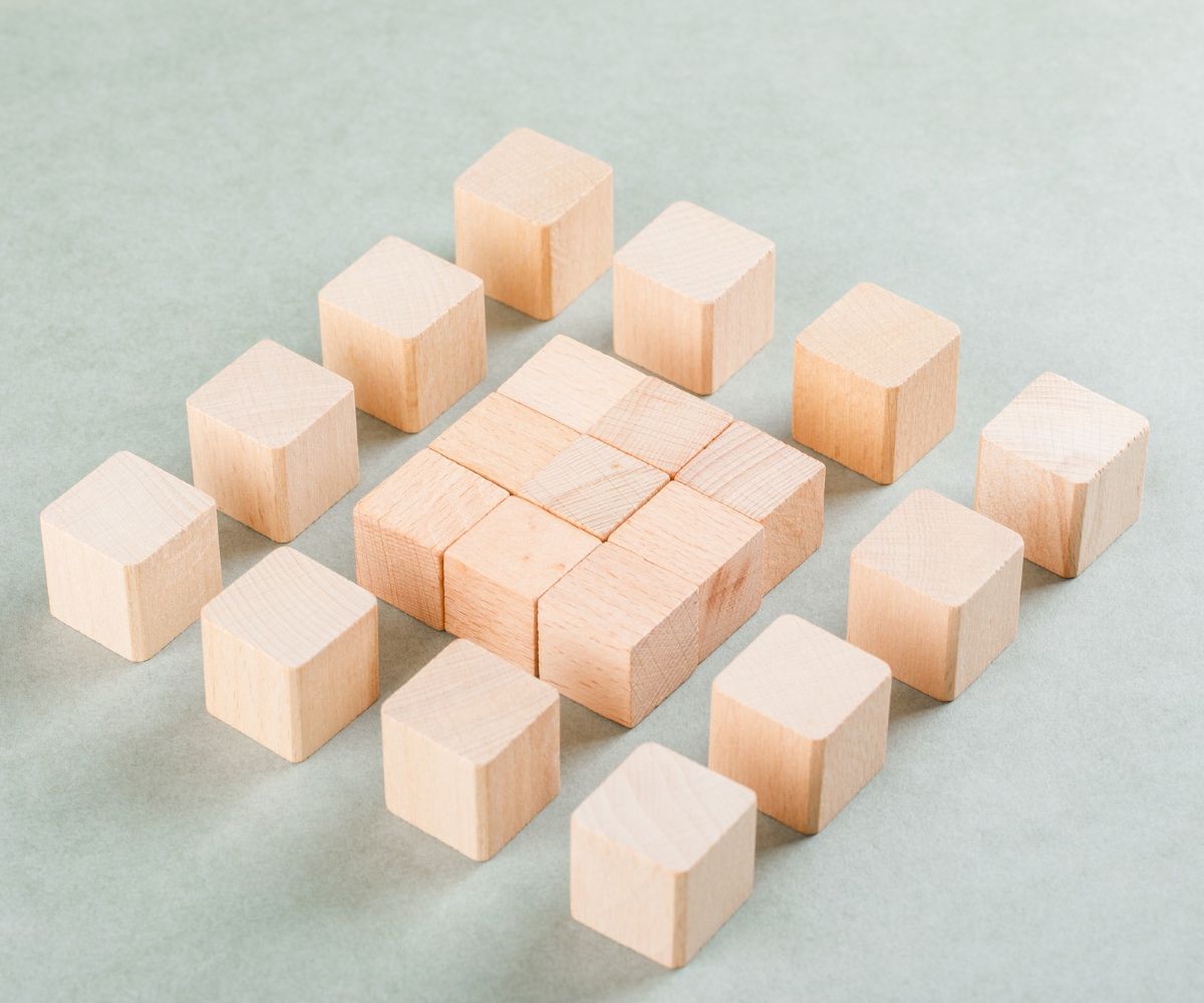 Nine light-colored wooden blocks placed in a square shape surrounded by 12 blocks in a square shape.