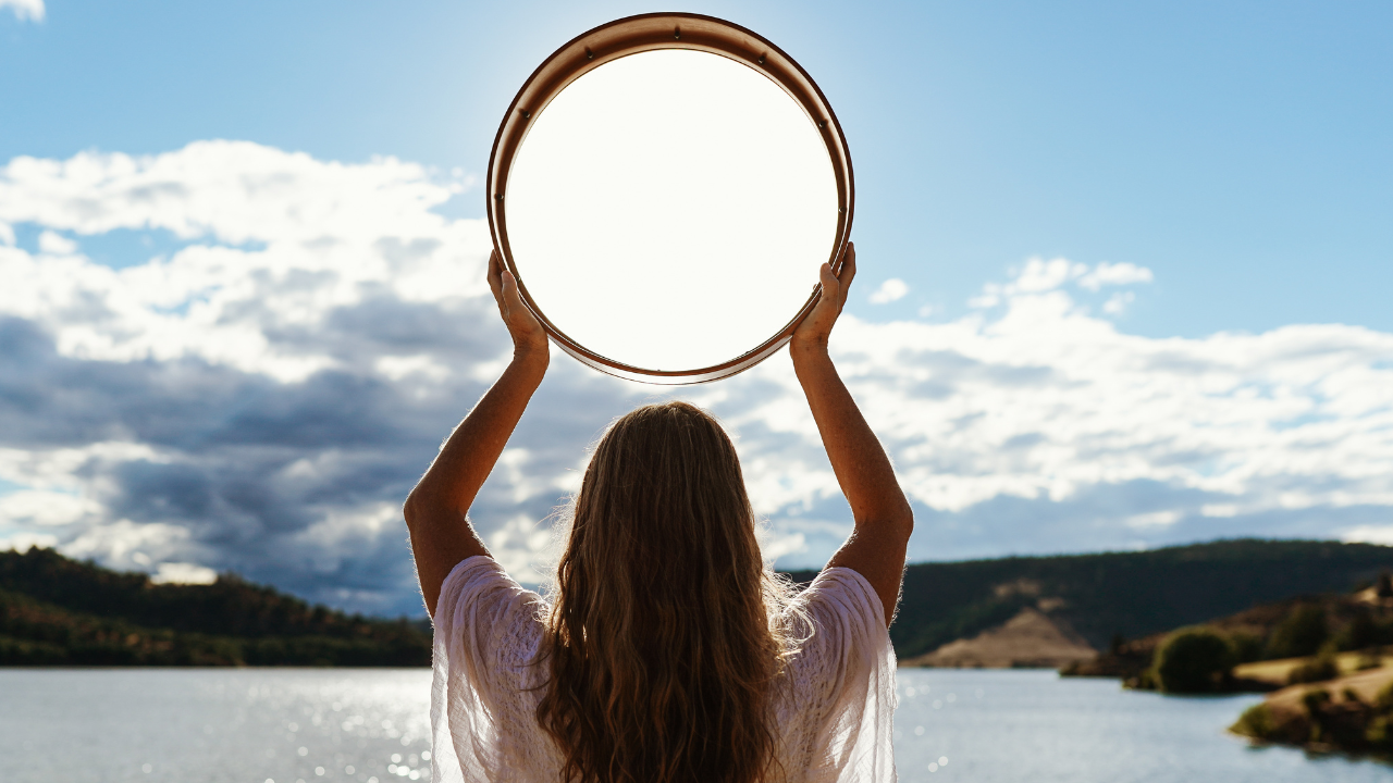 Krista Holland protégé of Layne Redmond with a frame drum held over head.