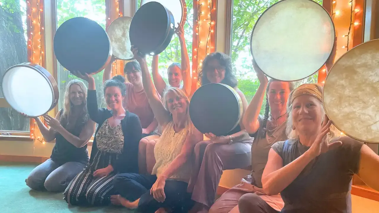 Krista Holland and women holding frame drums up in the airwidth="1280" height="720"px