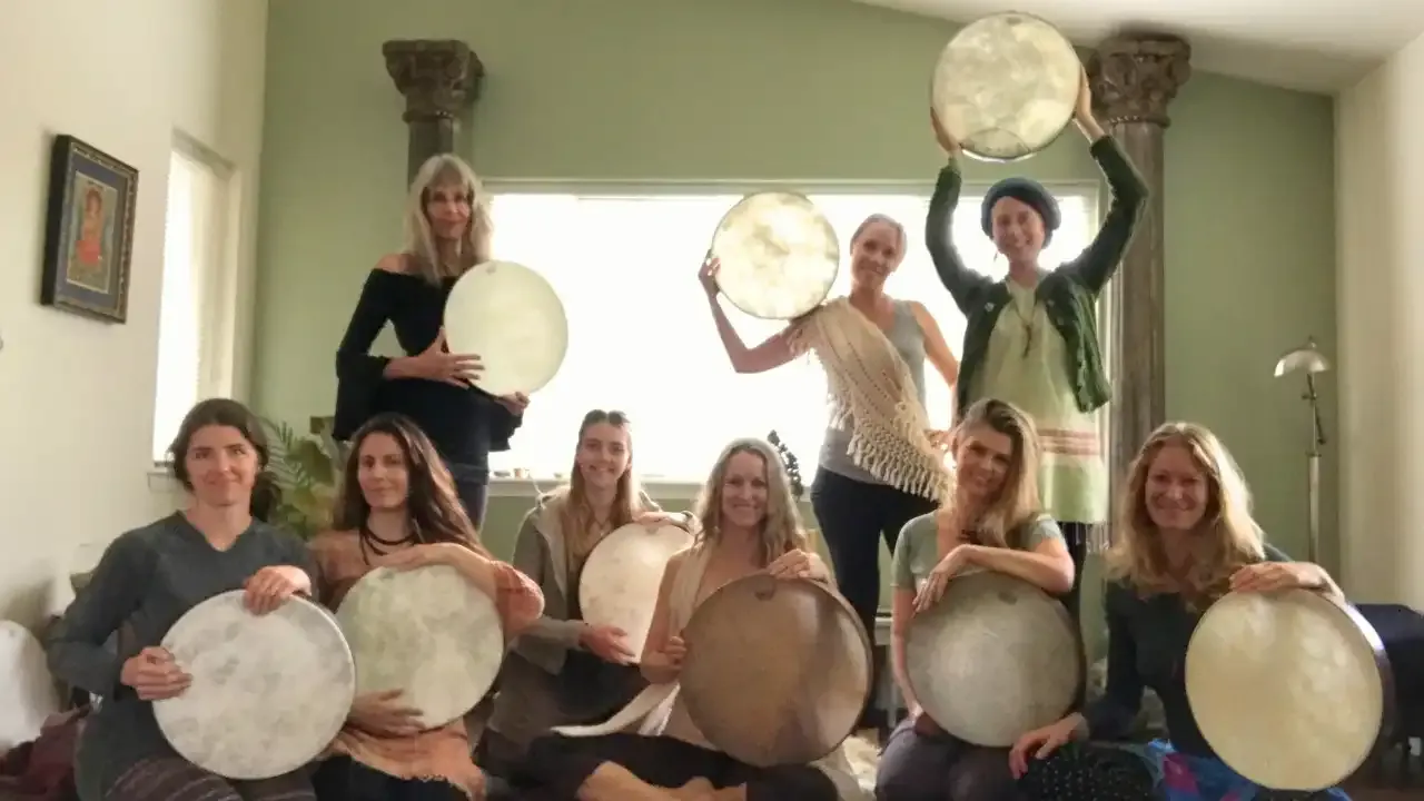 Krista Holland with a group a women with frame drums illuminated by the light width="1280" height="720"px