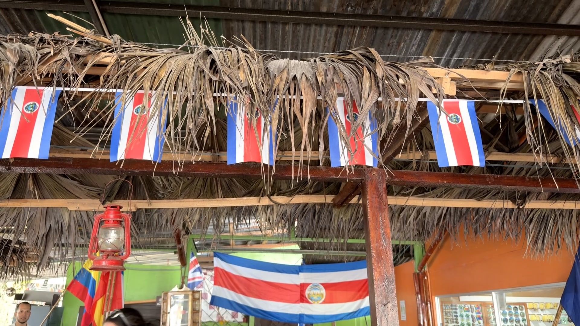 A Limon Costa Rica cruise port stop: local market with thatched roof and Costa Rican flags