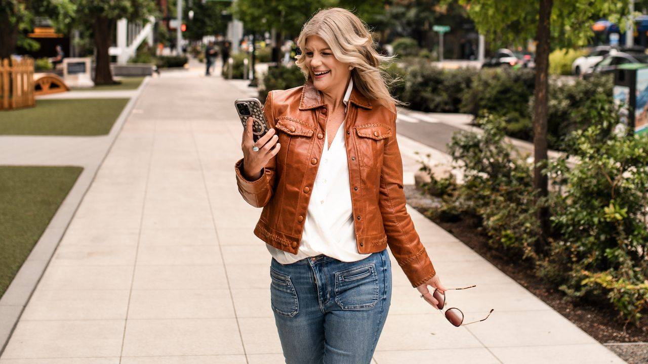Stacey Salyer walking down a city sidewalk looking at her phone