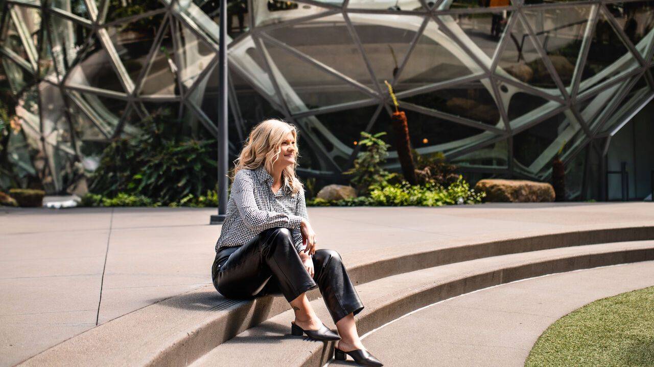 Stacey Salyer seated on stone steps in front of a modern glass building