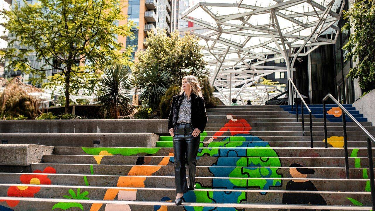 Stacey Salyer standing on colorfully painted city steps, looking into the distance