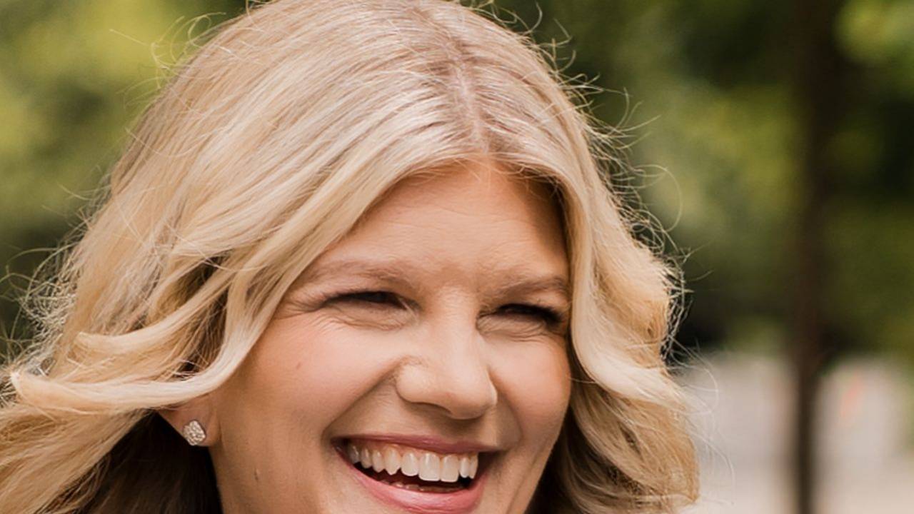 Stacey Salyer laughing on a garden path surrounded by green foliage