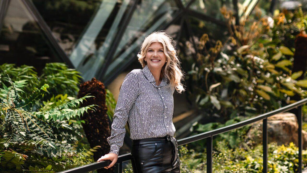 Stacey Salyer standing on a garden walkway outside a modern glass building