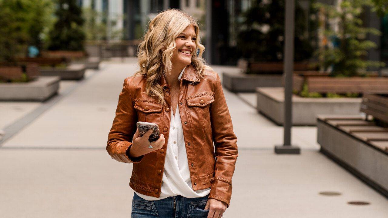 Stacey Salyer laughing while walking with her phone in a city plaza