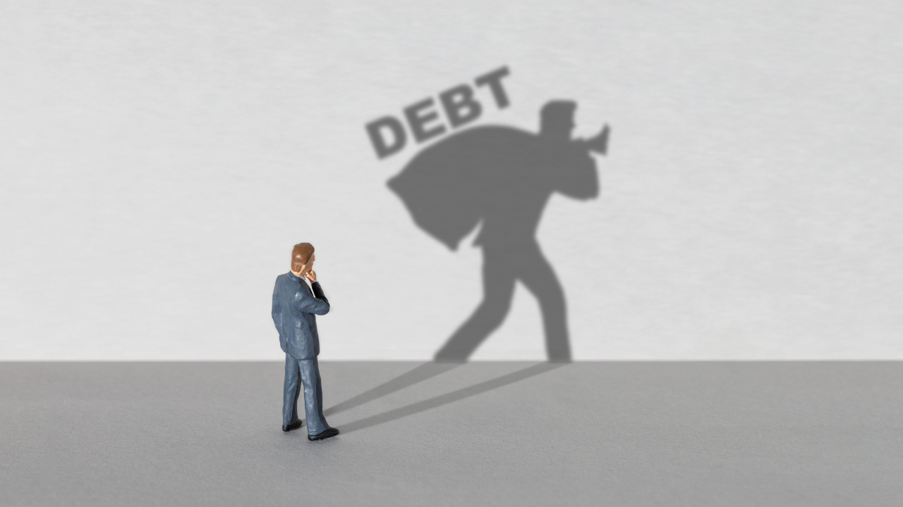 Man staring at his shadow with debt lurking in his shadow, a blog post from advice-only planner, Calgary