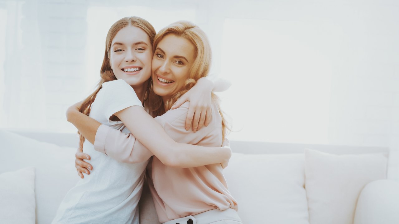 A smiling mother and teenage daughter embracing