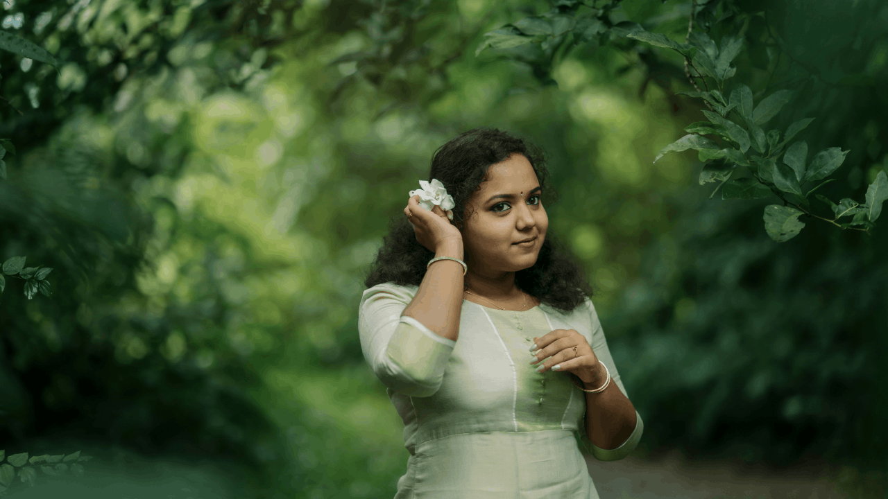 A woman wearing a white dress is standing in the forest.