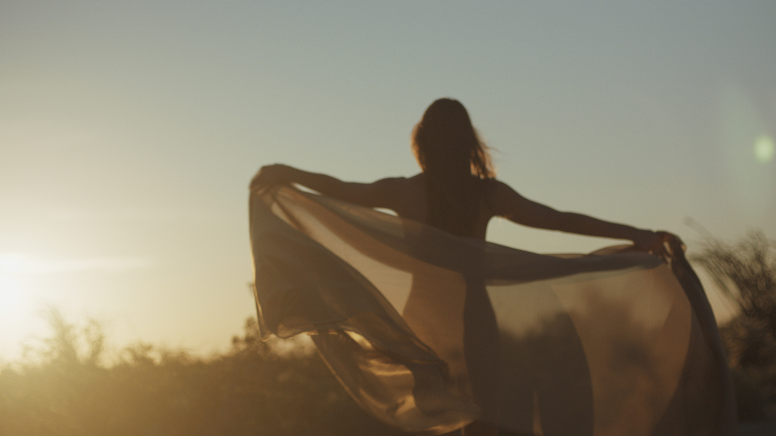 Woman holding a sheer veil in the morning sun