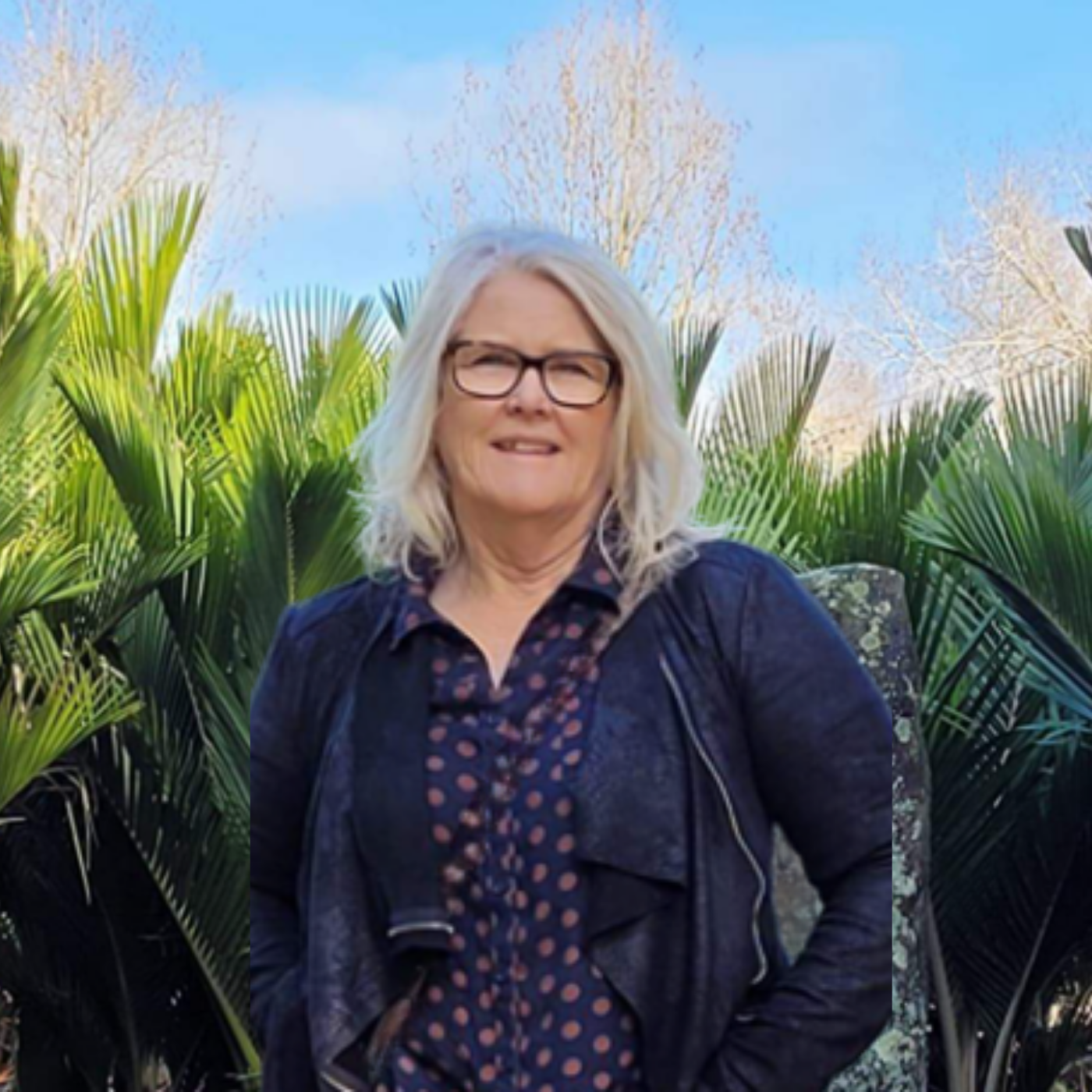 Sandra, founder of Beyond the Chaos, standing among the palms