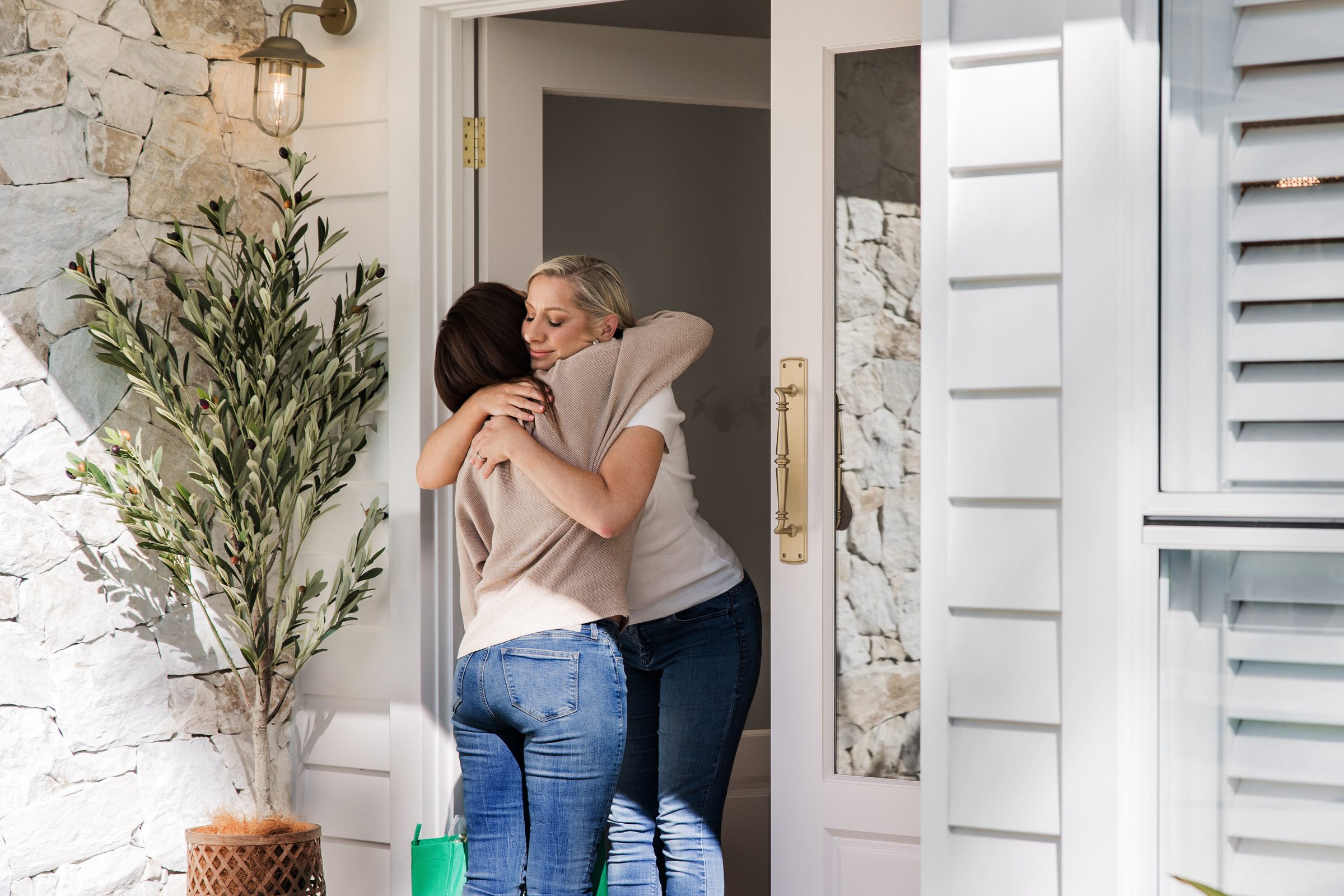 A friend arriving at the door with a bag of groceries, held in a hug
