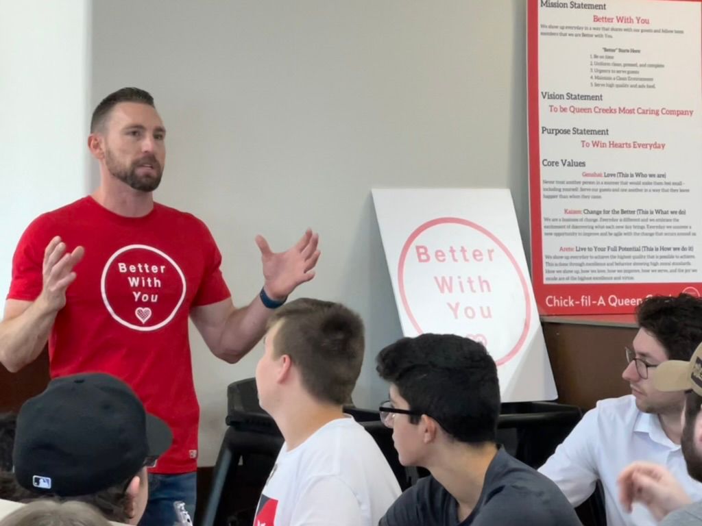 Jason teaching his team in the Better With You shirt