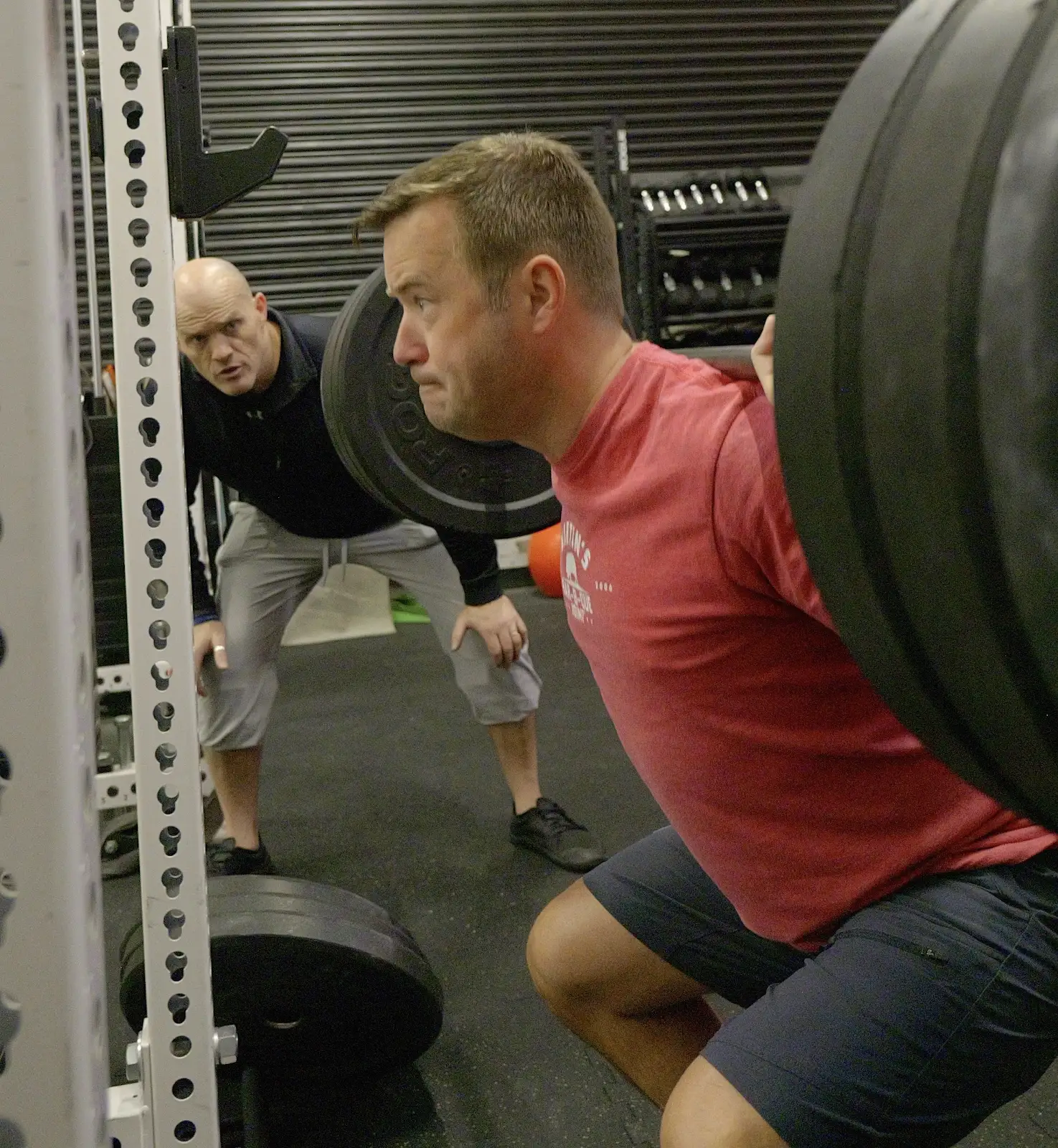 Ben McDonald closely observing a client's barbell squat