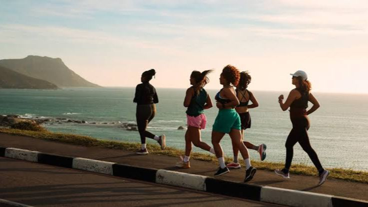 group of women runners running outside together by the beach