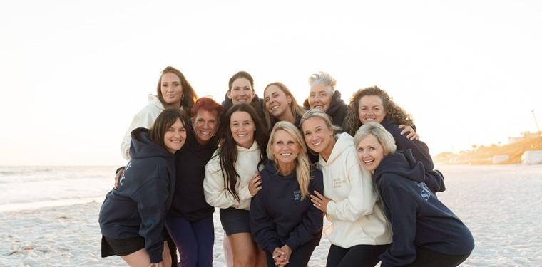 Retreat group in Seen Known Paid hoodies on the beach at sunset
