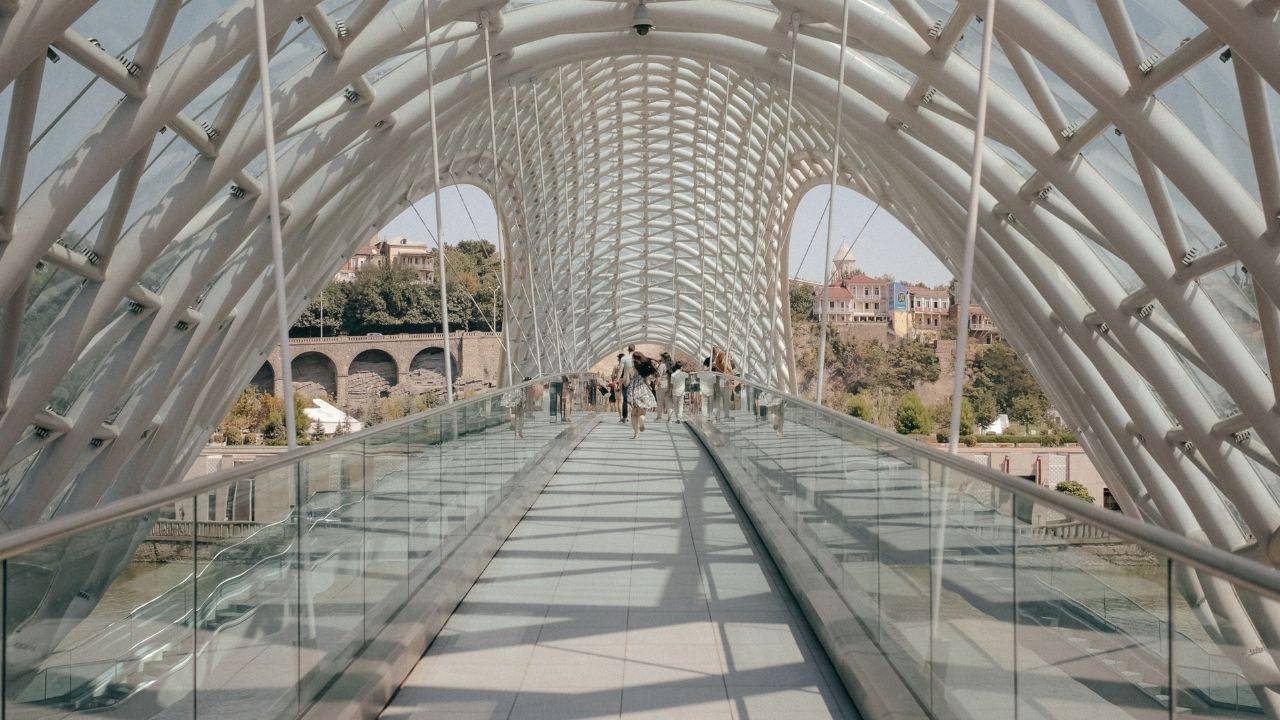 People walking across a modern white pedestrian bridge, representing career legacy and leadership impact that continues beyond one leader’s direct involvement.