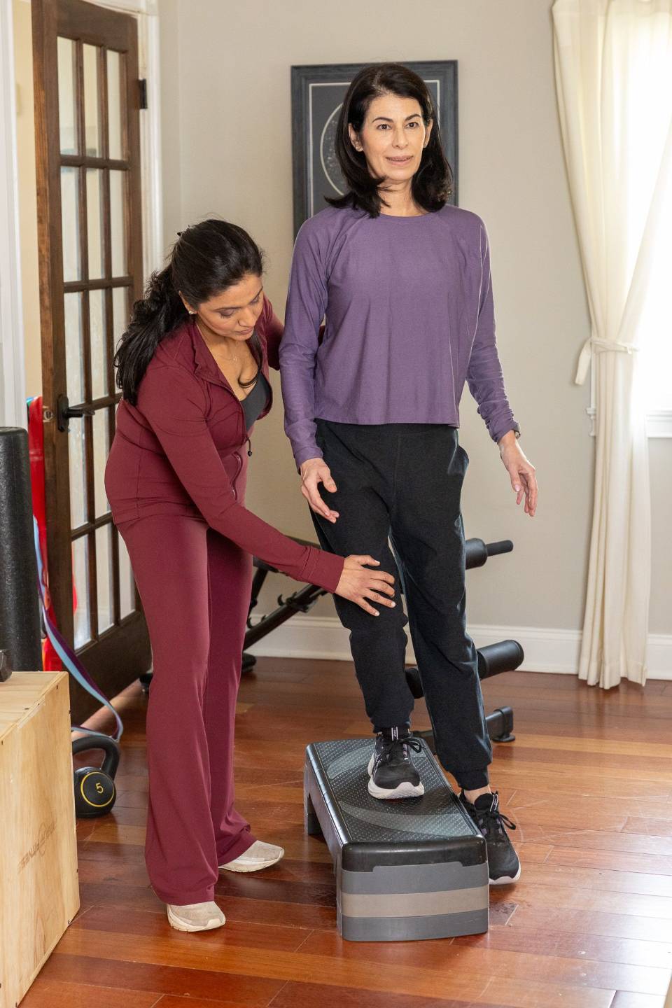 Dr. P checking a client's knee alignment during a step-up