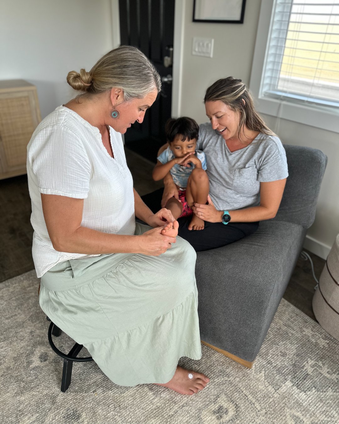 Amber Bodily reading a child's foot while his mother holds him