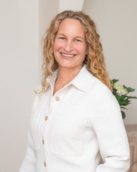 Carolyn Kaplan, smiling, wearing a white jacket