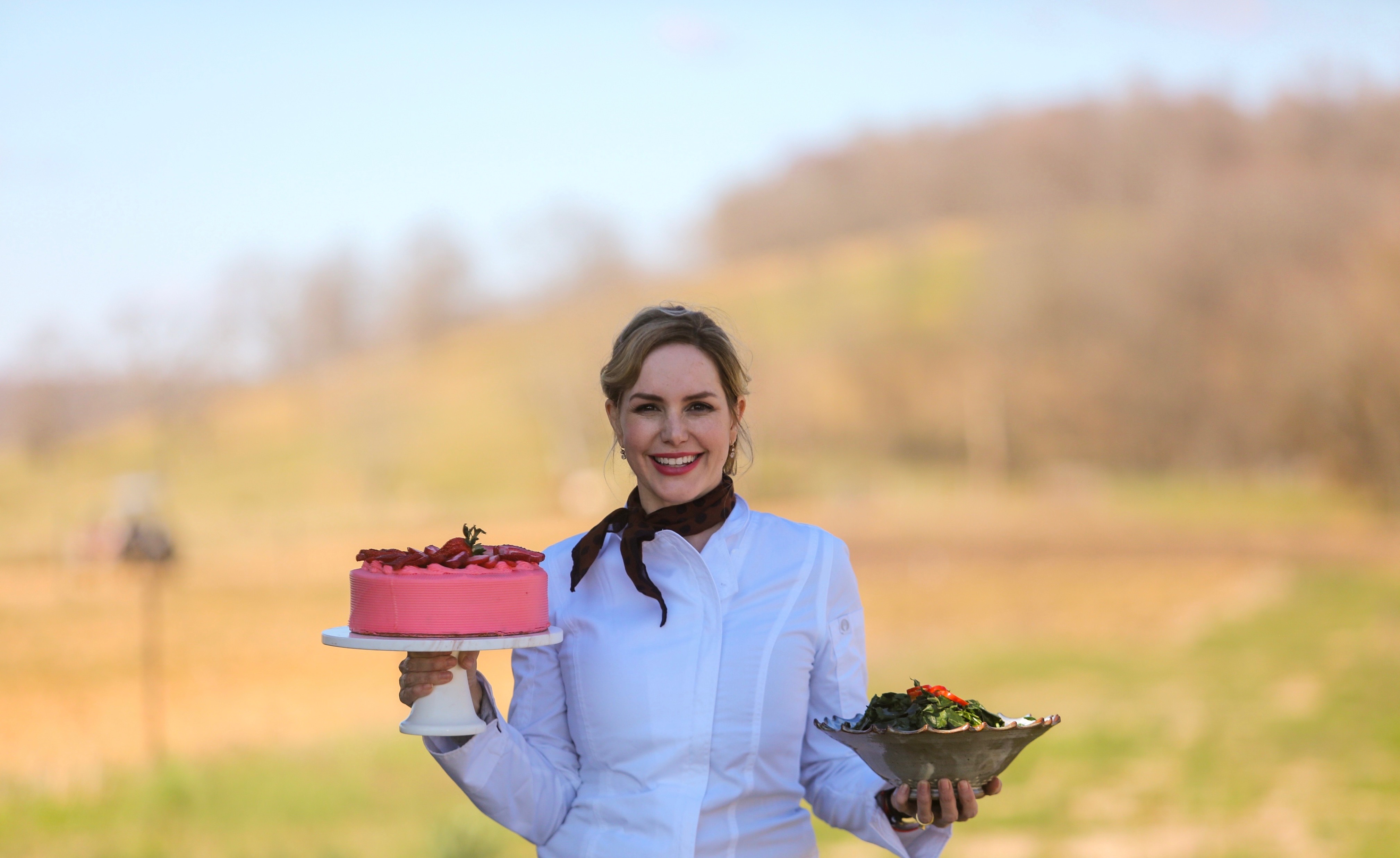 Mee McCormick in chef whites holding a pink cake