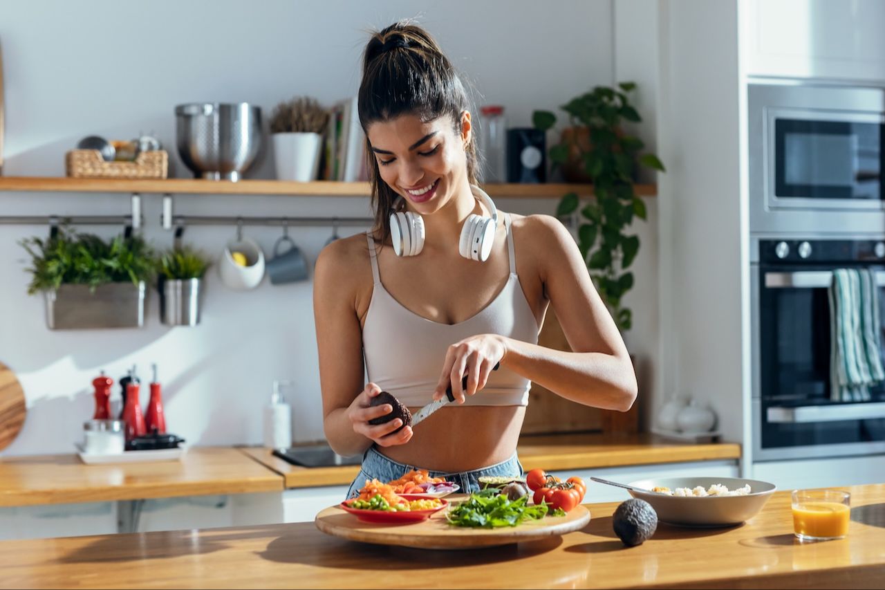 Sportiva che prepara un pasto sano ed equilibrato seguendo un piano alimentare per atleti
