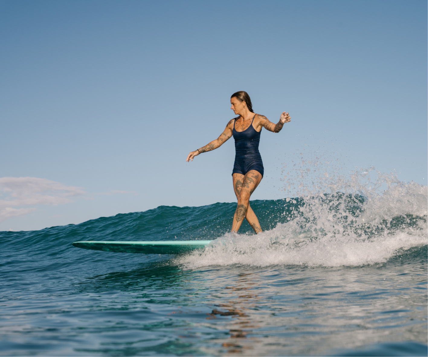surfer girl longboarder riding a beautiful wave, smiling while surfing at the surf retreat, facing blank pages surfing
