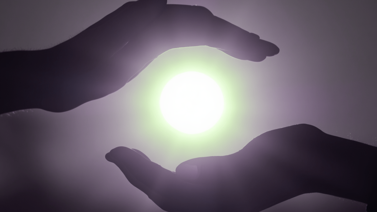 Two hands silhouetted around a glowing orb of light, cradling without gripping - representing the line between care that holds space and control that quietly closes it.